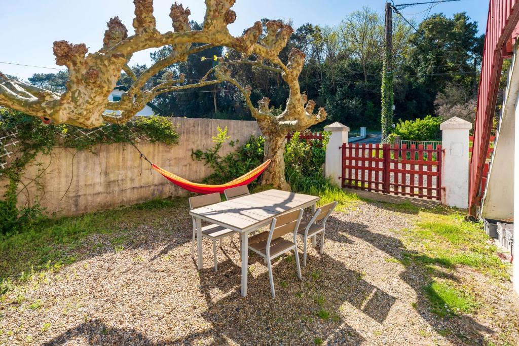 a table and a hammock next to a tree at Joli T3 Pays Basque Tarnos Landes in Tarnos