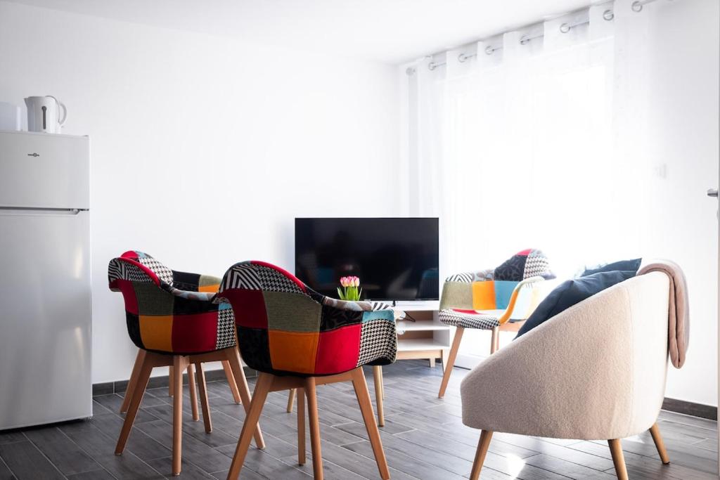 - un salon avec des chaises, une table et une télévision dans l'établissement La Tour Penchée, à Oye-Plage