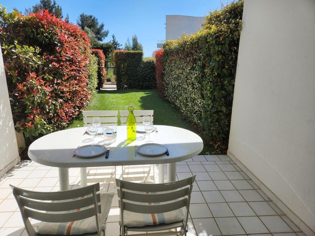 - une table blanche avec des chaises et une bouteille de vin dans l'établissement Nouveau Douceur à Bandol, à Bandol