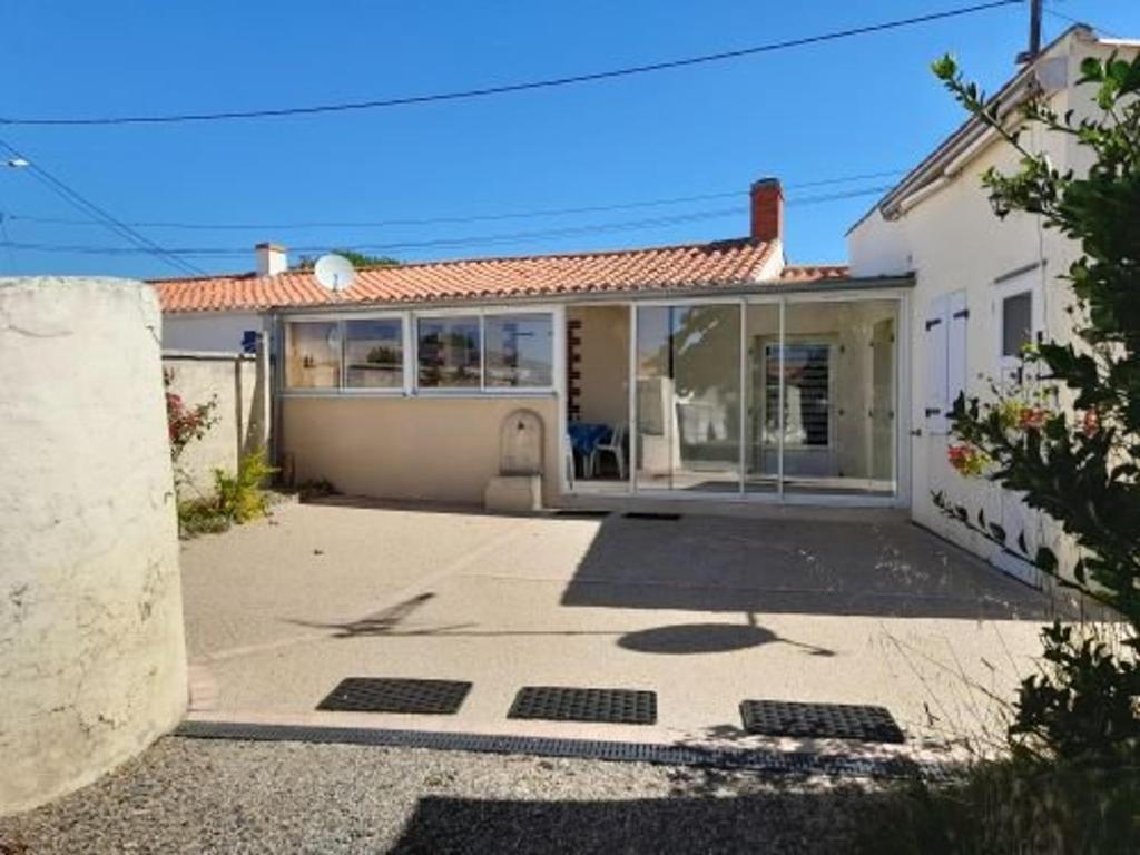 une maison blanche avec beaucoup de fenêtres dans l'établissement Charmante villa rénovée avec grand jardin clos, véranda, 3 chambres, proche de la plage et des activités - FR-1-324-503, à Saint-Gilles-Croix-de-Vie
