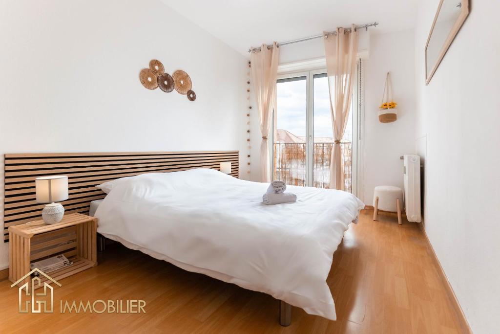 une chambre blanche avec un lit et une fenêtre dans l'établissement Le Refuge - Colmar, à Colmar
