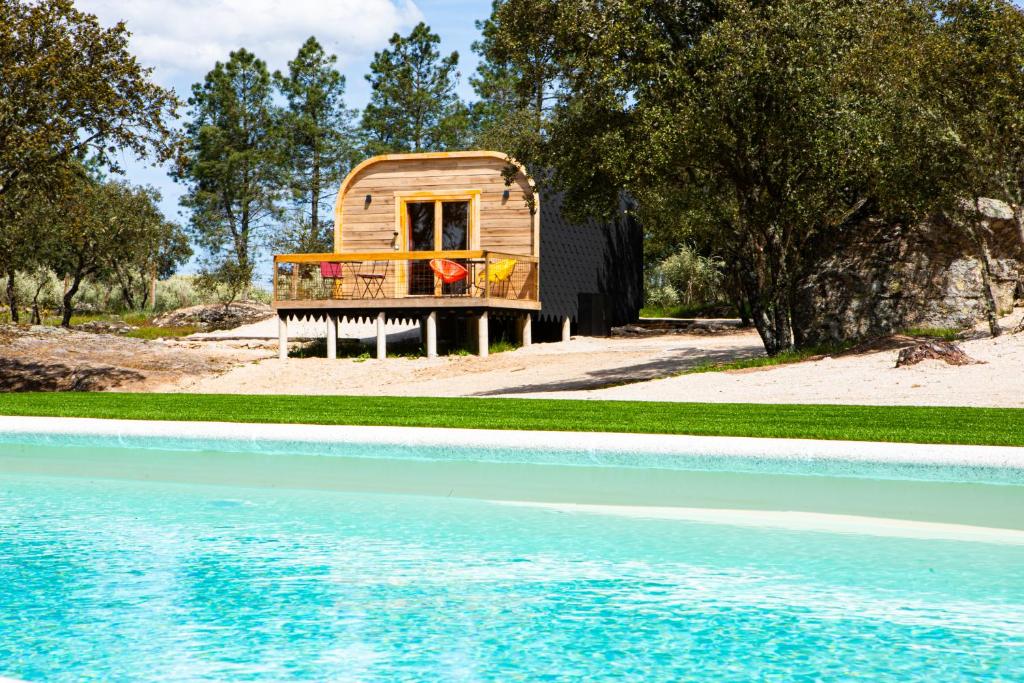 a small wooden cabin next to a pool of water at Quinta do Prado Verde in Vilar Formoso
