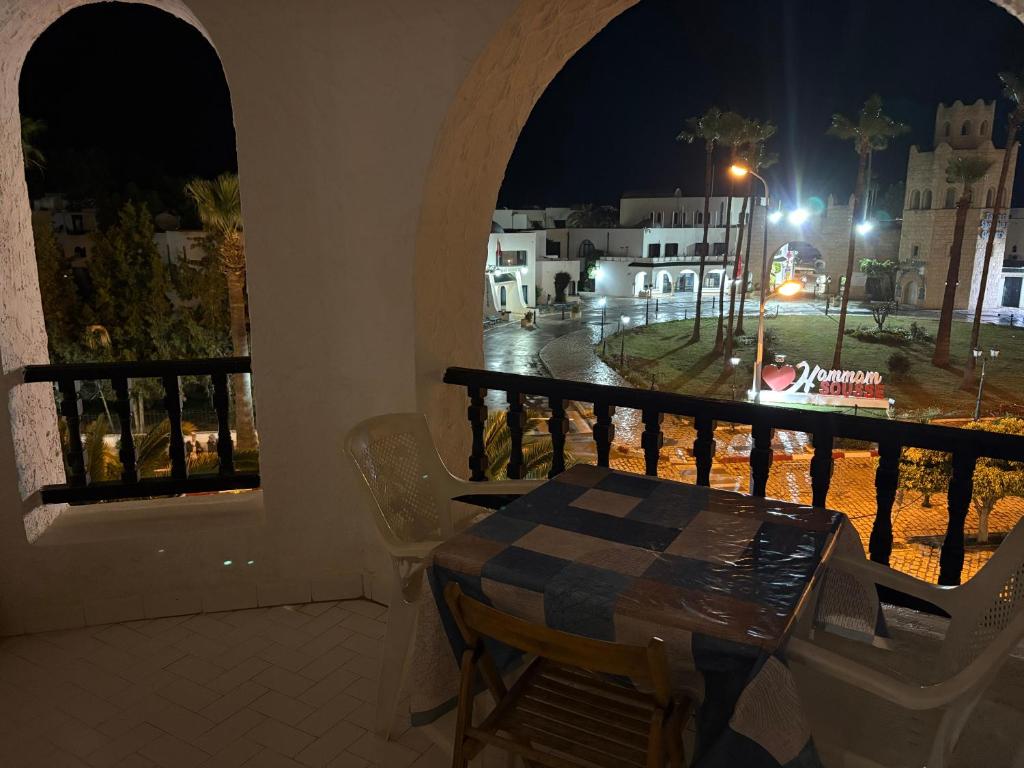 a table and chairs on a balcony at night at Bungalow avec une vue panoramique in Sousse