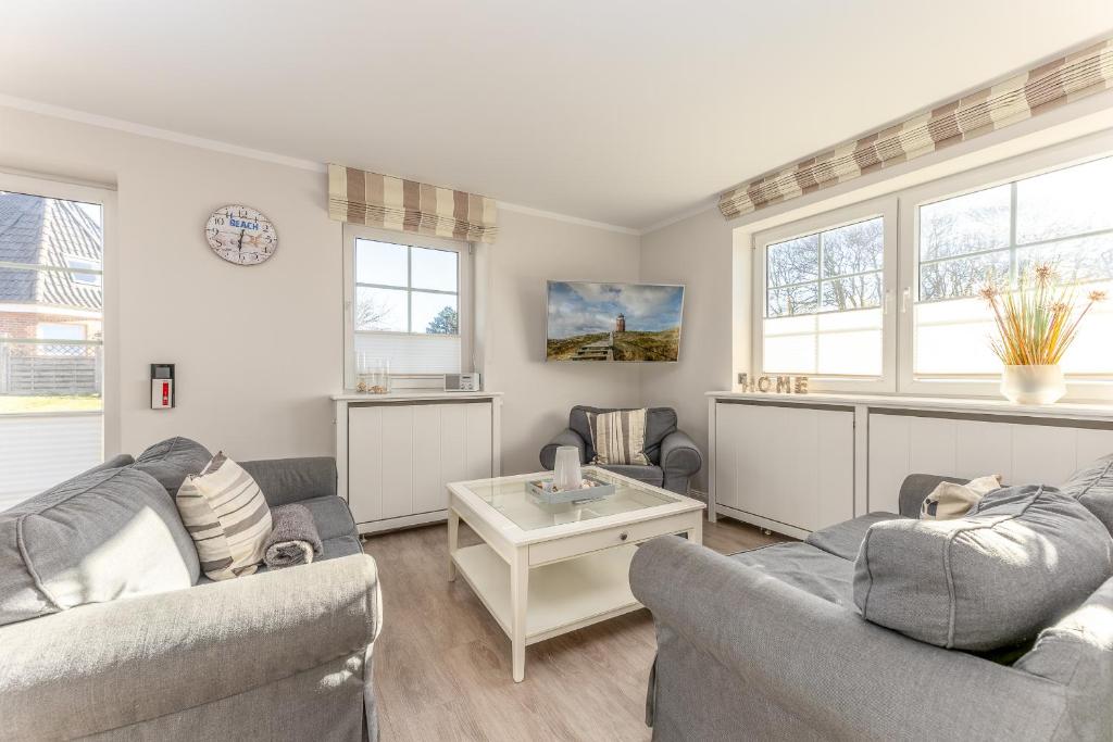 a living room with two couches and a table at Appartement Meeresleuchten - Nicolinenhof in Wenningstedt