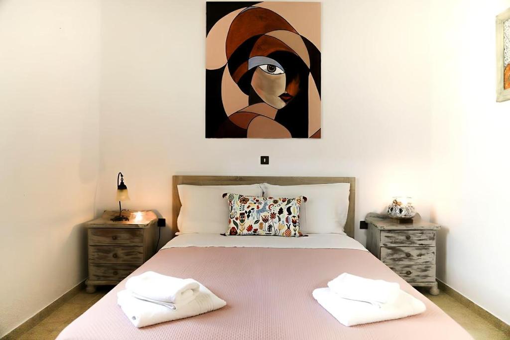 a bedroom with a bed with a painting on the wall at Rodis Cycladic Holiday House in Naousa