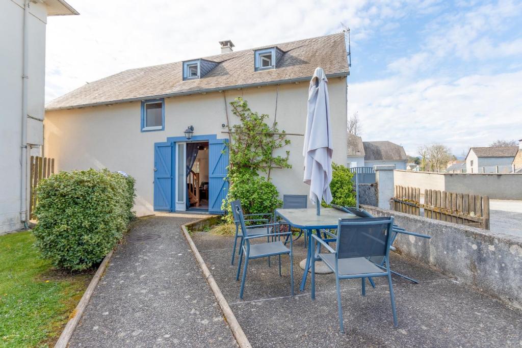 a table with chairs and an umbrella in front of a house at Gite La Bergerie près de Lourdes in Adé