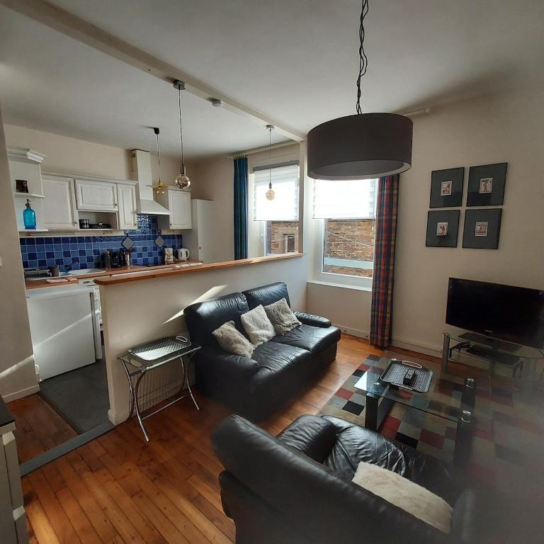 un salon avec un canapé et une cuisine dans l'établissement appartement chic et calme en plein centre-ville, à Paimpol