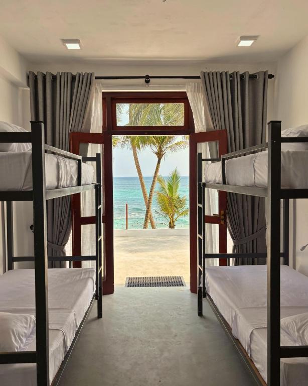 a room with bunk beds with a view of the beach at Surfing Tusker - Thalpe in Talpe