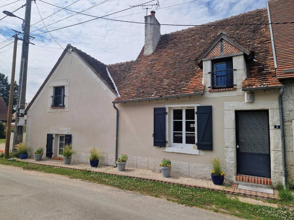 une maison blanche avec des plantes en pot dans une rue dans l'établissement Maison gîte proche du Château de Chambord, à Maslives