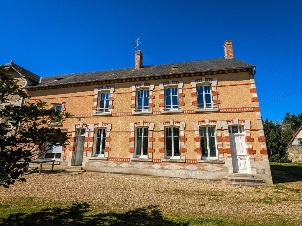 a large brick building with blue windows on a clear day at Moulin paisible en Berry avec étang privé, proche du Château de Valençay et Zoo de Beauval - FR-1-591-18 in Chabris