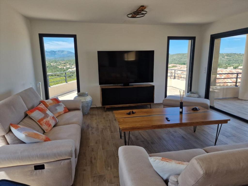 un salon avec deux canapés et une télévision dans l'établissement Villa vue mer, montagne piscine, à La Gondière