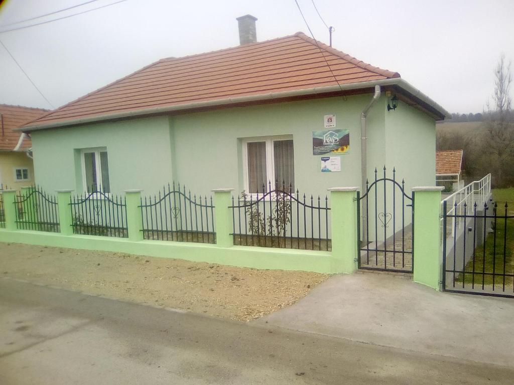a small green and white house with a fence at KOÓS VENDÉGHÁZ in Uppony