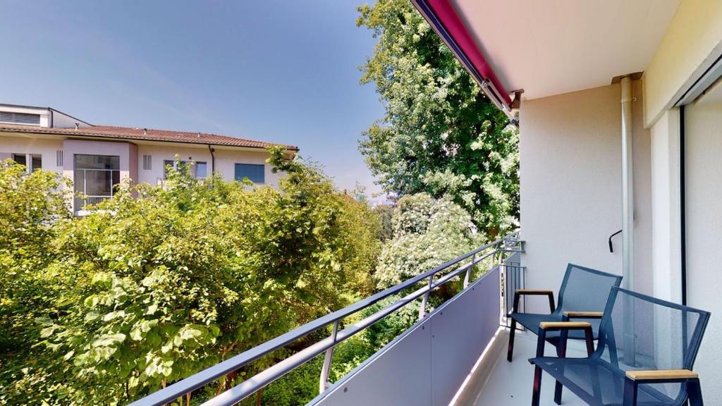 two blue chairs on a balcony with trees at Cute and central studio - Sun 11 in Zurich