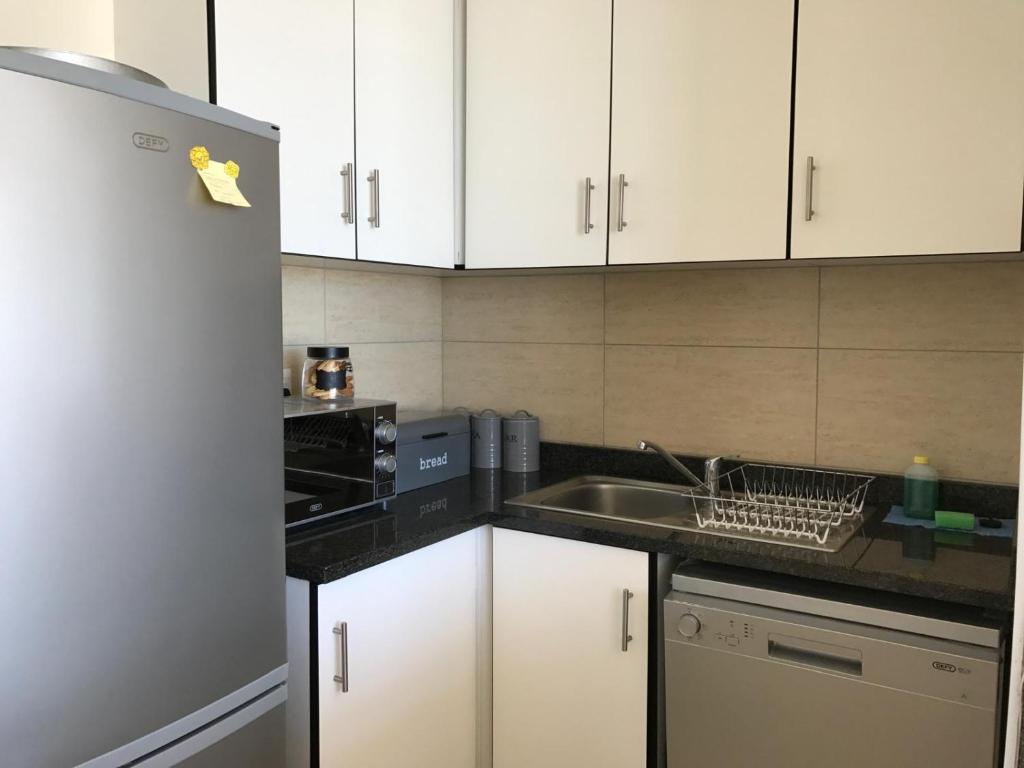 una cucina con mobili bianchi, un lavello e un frigorifero di Serenity 905 a Durban
