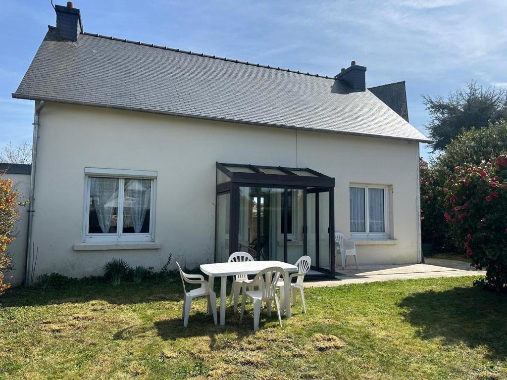 une maison blanche avec une table et des chaises dans la cour dans l'établissement Le Repaire de Plérin - Plage et bourg, à Plérin