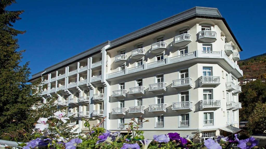- un grand bâtiment blanc avec balcon et fleurs violettes dans l'établissement B&B HOME Brides-les-Bains Les 3 Vallées, à Brides-les-Bains