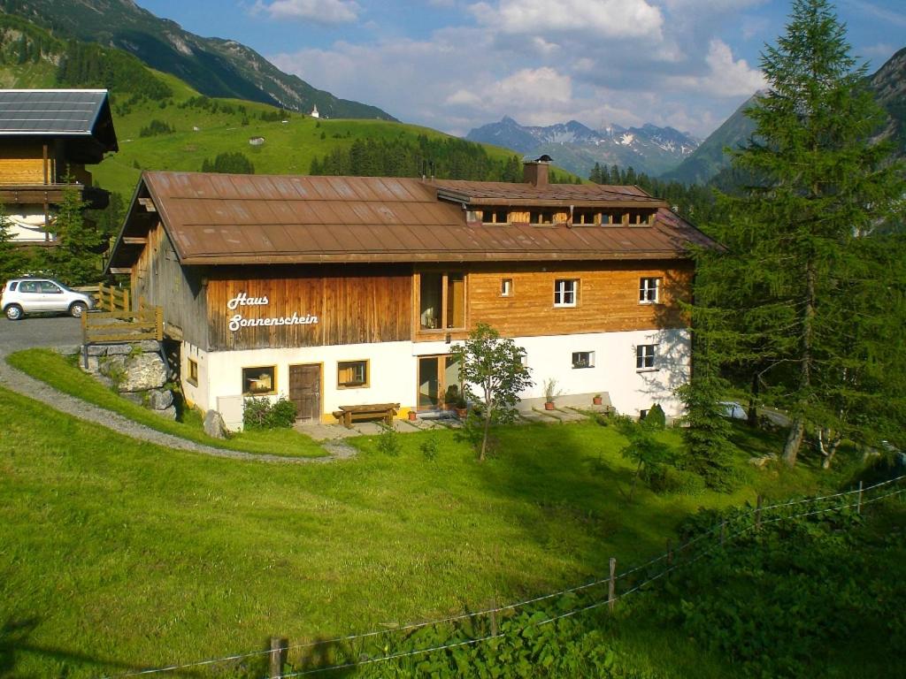 a house in a field with a car parked next to it at Haus Sonnenschein in Warth am Arlberg
