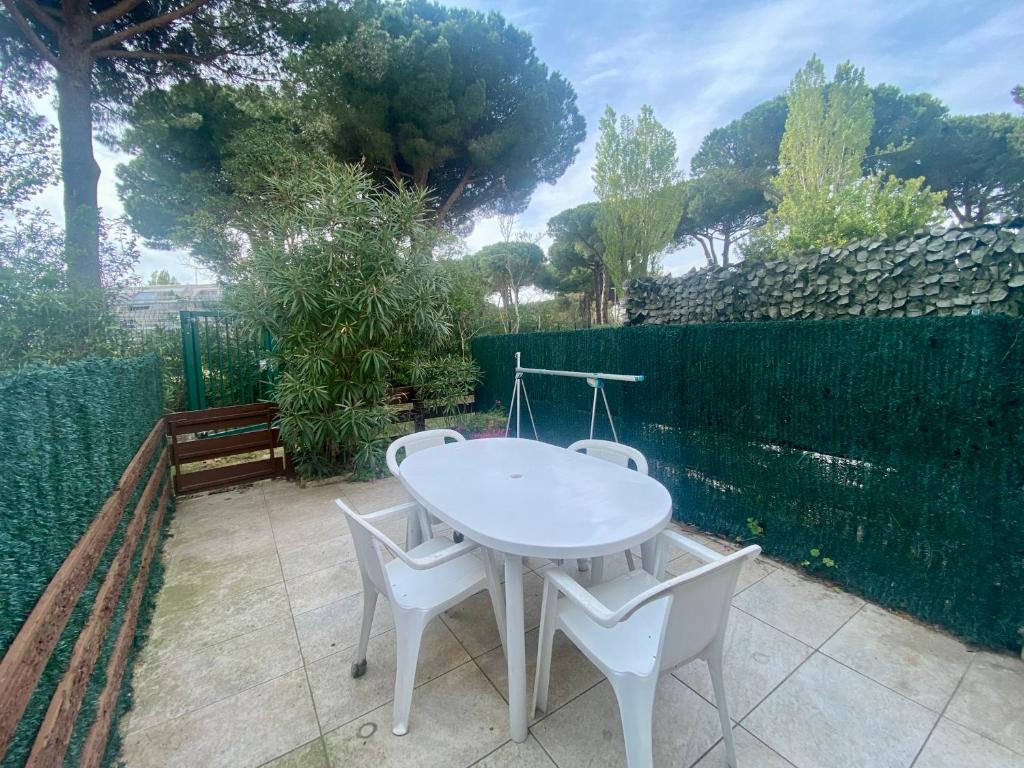 une table blanche et des chaises sur une terrasse dans l'établissement Famille & Farniente - Terrasse verdoyante au couchant, à La Grande Motte