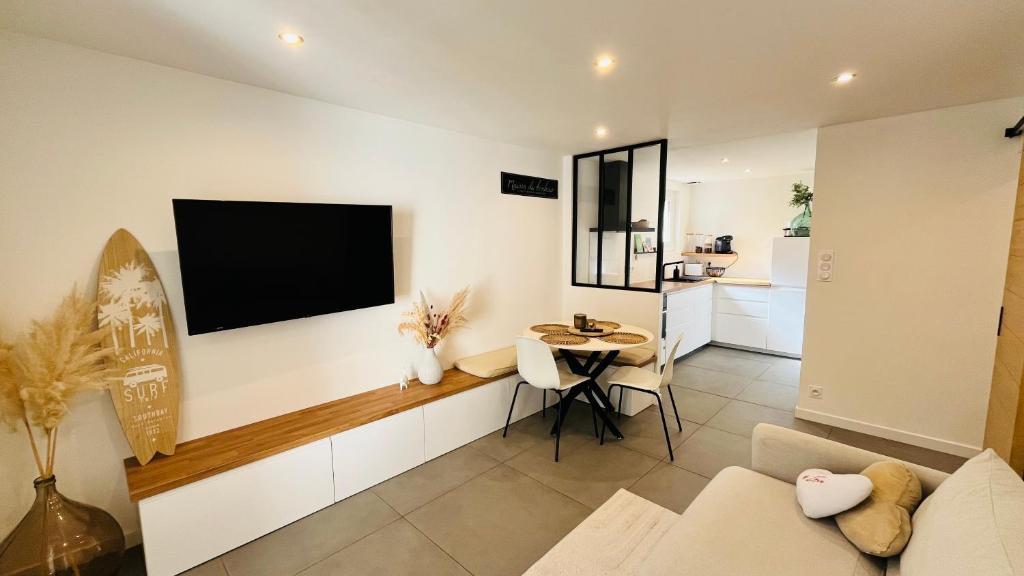 un salon avec une télévision à écran plat sur un mur dans l'établissement T2 des pins, océan et soleil, à Saint-Jean-de-Monts