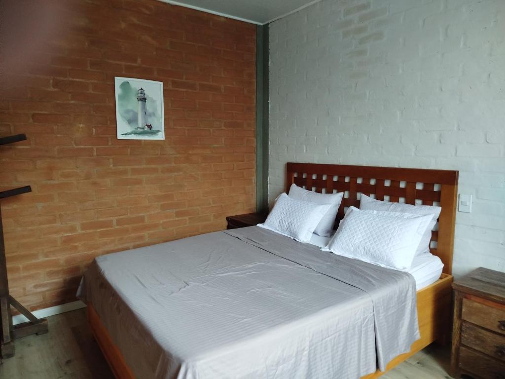 ein Schlafzimmer mit einem Bett mit einer Ziegelwand in der Unterkunft Casa Quinta do Paiol in São Bento do Sapucaí