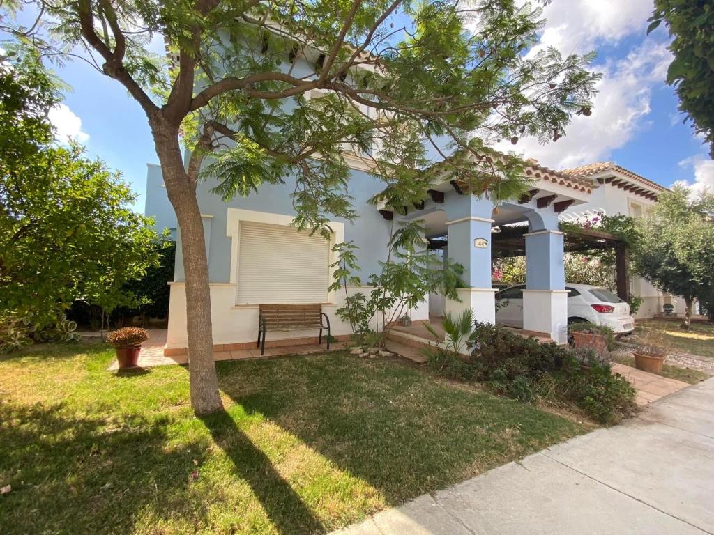 a house with a tree in the yard at Mar Menor Golf Resort , La maison bleue, villa piscine privée in Los Martínez
