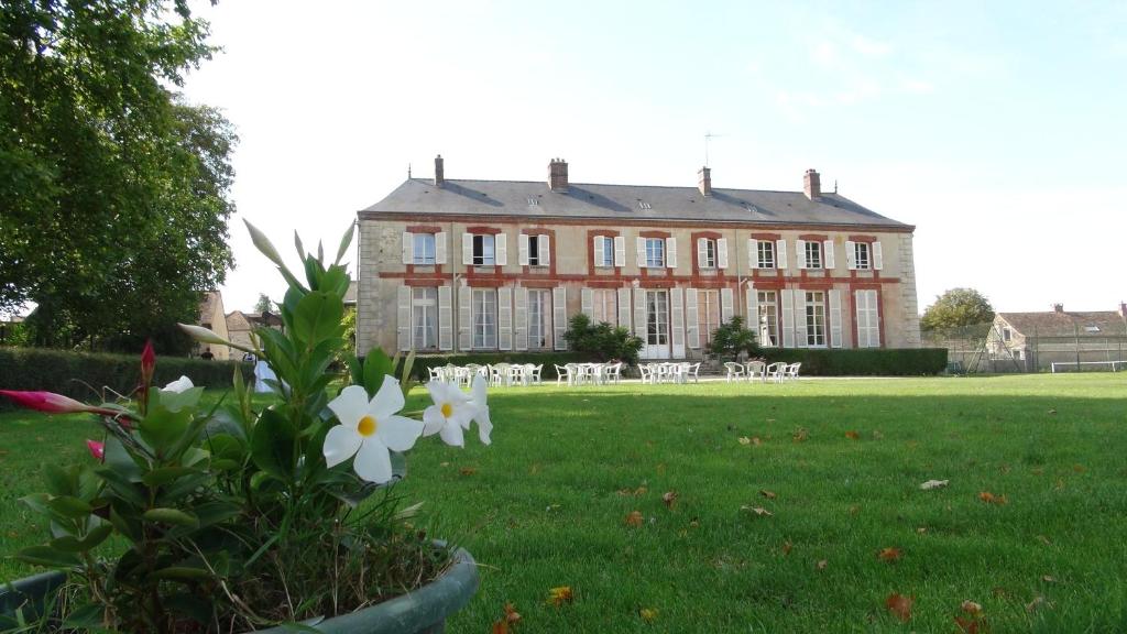 une grande maison avec des fleurs blanches devant elle dans l'établissement Le Domaine d'Euclide, à Boissy-sous-Saint-Yon