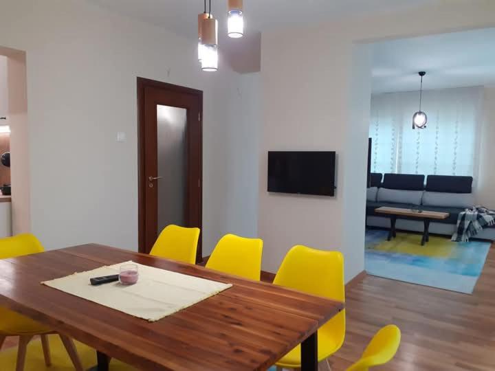 Un comedor con una mesa de madera y sillas amarillas. en Statevi Guest Apartment 1, en Velingrad