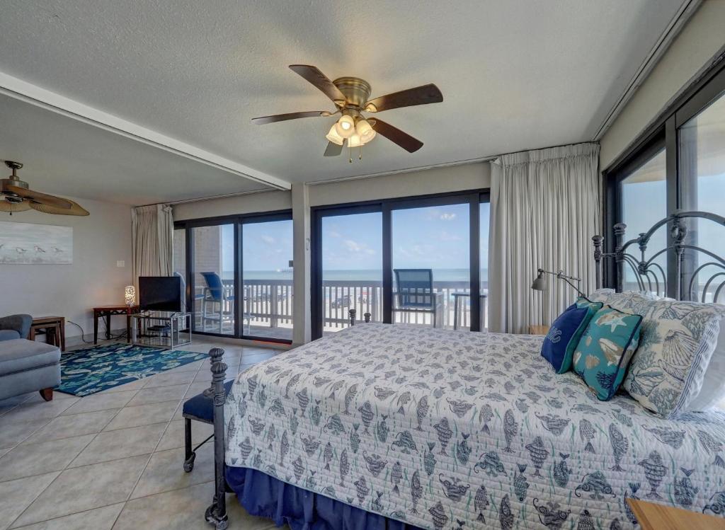 a bedroom with a bed and a ceiling fan at Island House BeachFront Condo Hotel in Corpus Christi
