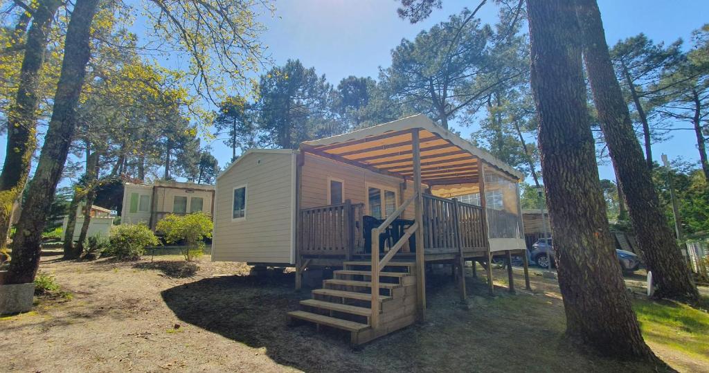 une petite maison avec un escalier à côté d'un arbre dans l'établissement Mobil-home climatisé 6 personnes, à Lège-Cap-Ferret