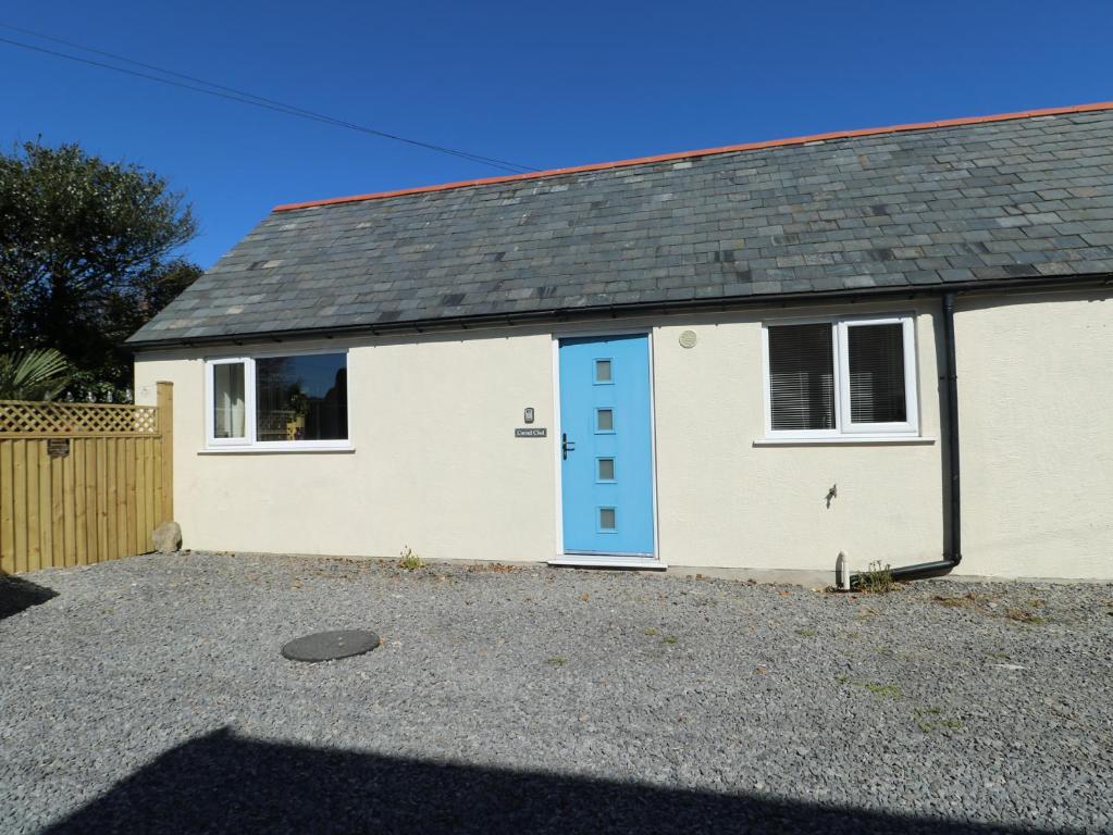 a white house with a blue door at Cornel Clud in Cemaes Bay