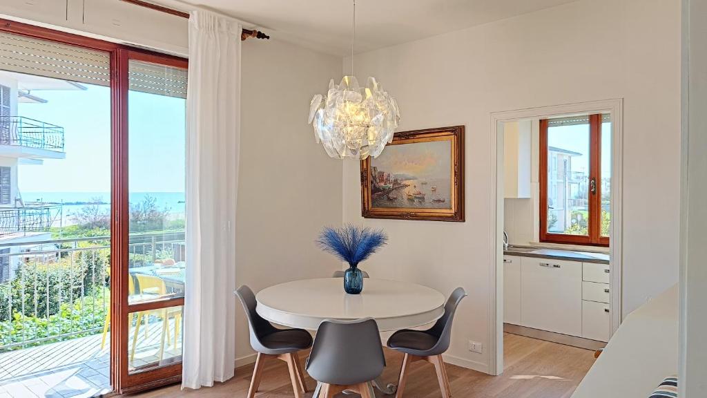 a dining room with a table and chairs and a chandelier at I Marosi Beach Apartment in Lido di Fermo