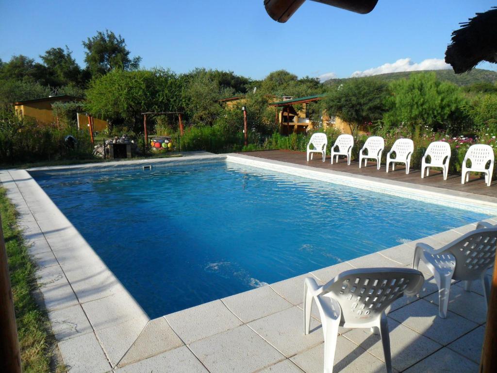 - une piscine avec des chaises blanches dans l'établissement Cabañas Mandala, à San Marcos Sierras
