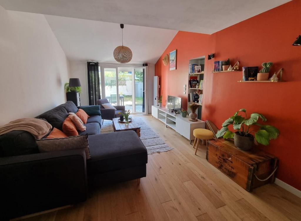 - un salon avec des murs orange et un canapé dans l'établissement maison indépendante, à Orvault