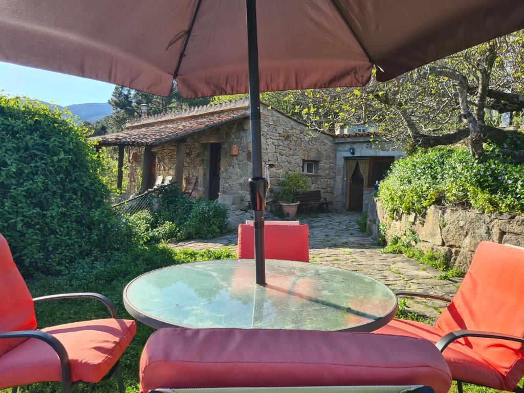una mesa de cristal y sillas bajo una sombrilla en El Valle, en Piedralaves