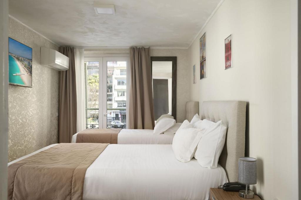 a hotel room with two beds and a window at Hotel des Congrès et Festivals in Cannes