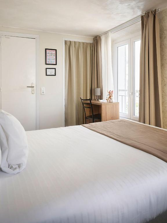 a bedroom with a large white bed and a desk at Hotel des Congrès et Festivals in Cannes