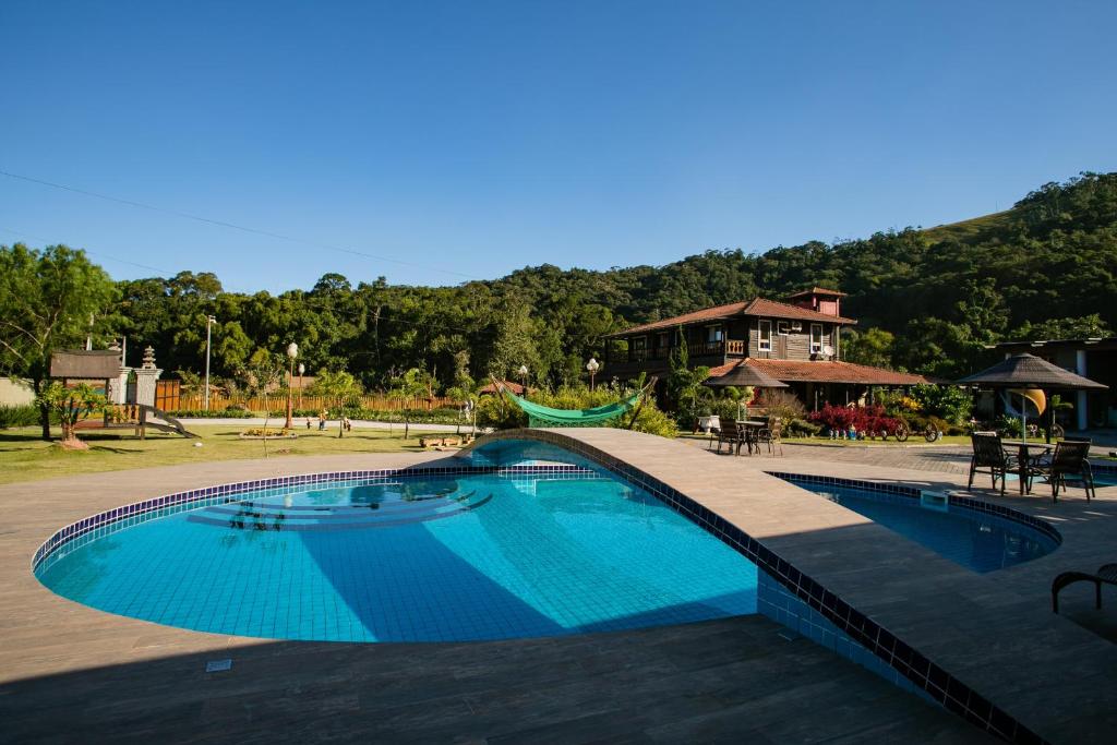 a large swimming pool with a playground and a house at Casa da Família no Sítio Mannes in Antônio Carlos