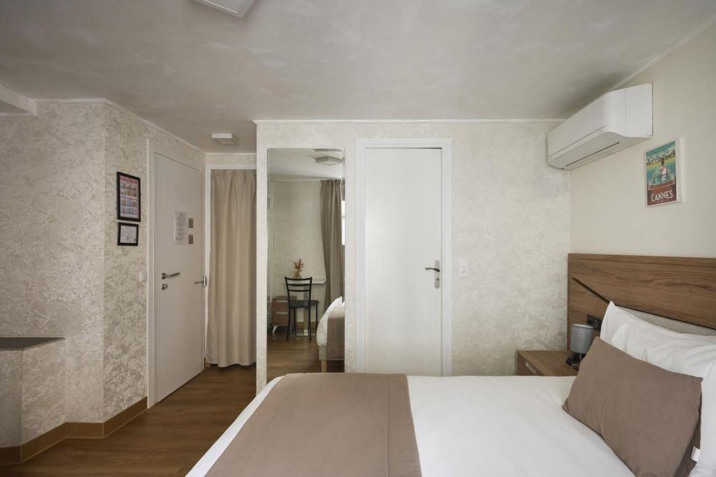 a bedroom with a white bed and a mirror at Hotel des Congrès et Festivals in Cannes