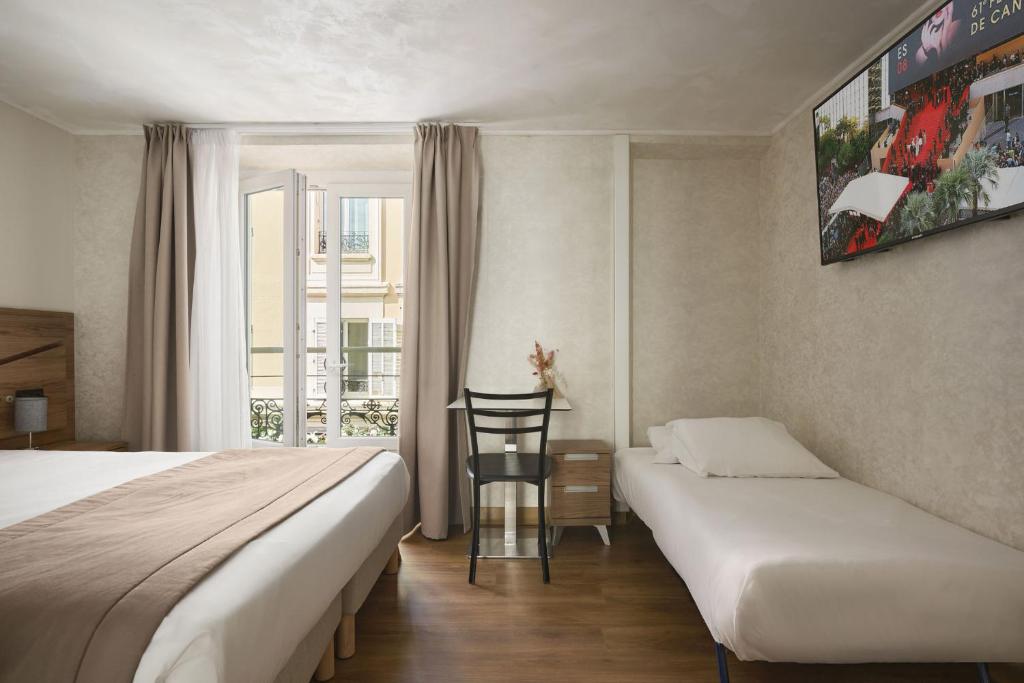 a hotel room with two beds and a chair at Hotel des Congrès et Festivals in Cannes