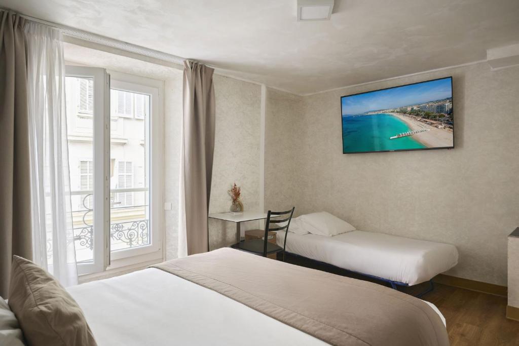 a hotel room with two beds and a window at Hotel des Congrès et Festivals in Cannes