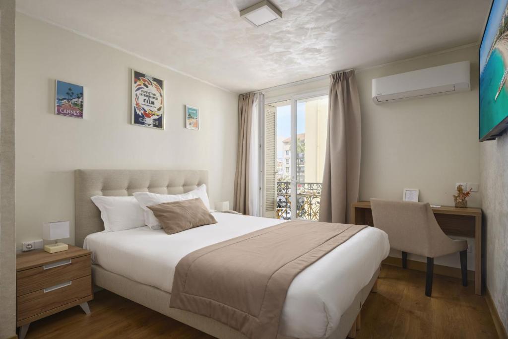 a bedroom with a bed and a desk and a window at Hotel des Congrès et Festivals in Cannes