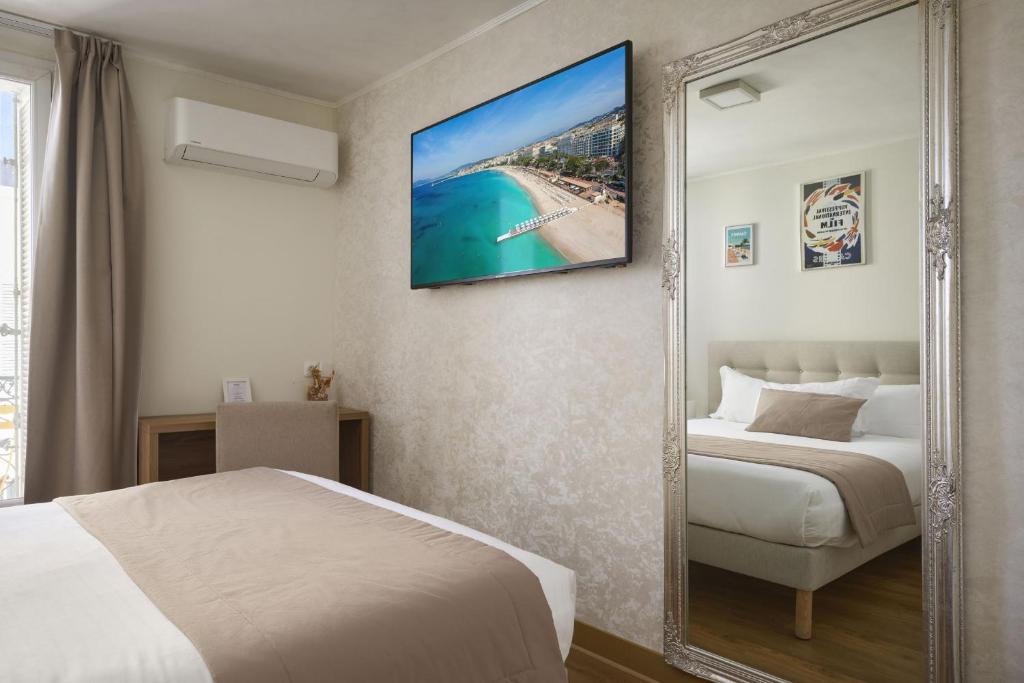 a hotel room with a bed and a mirror at Hotel des Congrès et Festivals in Cannes