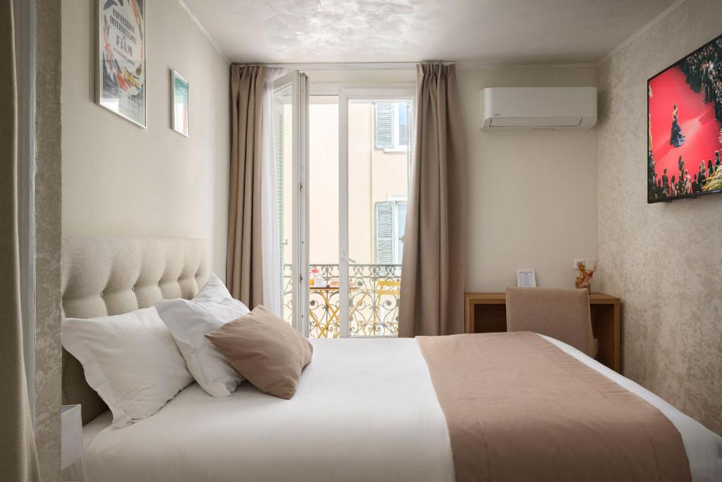 a bedroom with a large white bed with a window at Hotel des Congrès et Festivals in Cannes