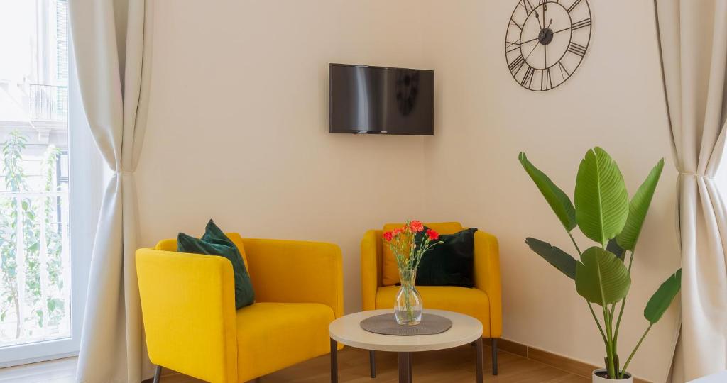 dwa żółte krzesła i stół z wazonem kwiatów w obiekcie Musto Suites & Rooms w mieście Neapol