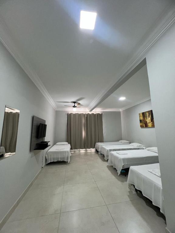 a room with four beds and a flat screen tv at Apartamento 101 - Suíte ampla para grupos e empresas in Patos de Minas