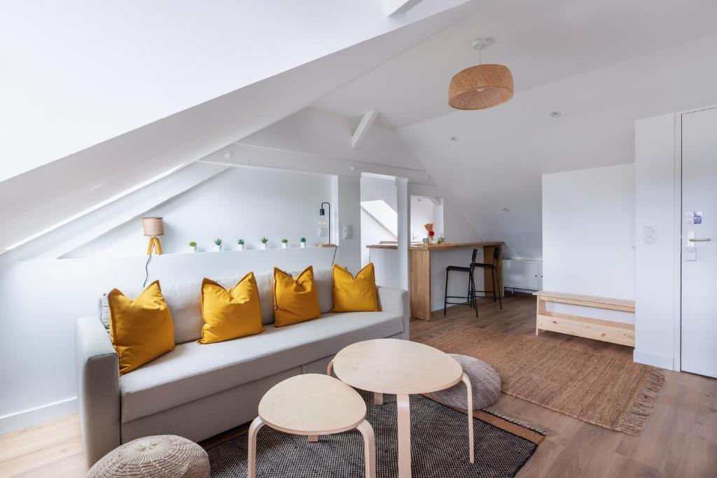 un salon avec un canapé et deux tables dans l'établissement Le Bourbonnais ~ Mansardé ~ Arrivée Autonome, à Montluçon