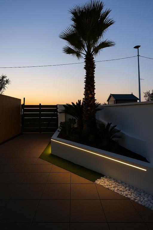 a palm tree sitting next to a wall with a light at AR Palace Hotel - Palermo in Isola delle Femmine