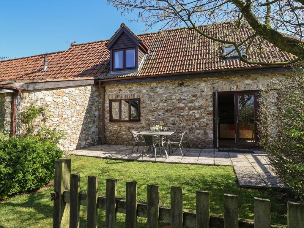 une maison en pierre avec une table dans la cour dans l'établissement Meadow Cottage, à Monkton
