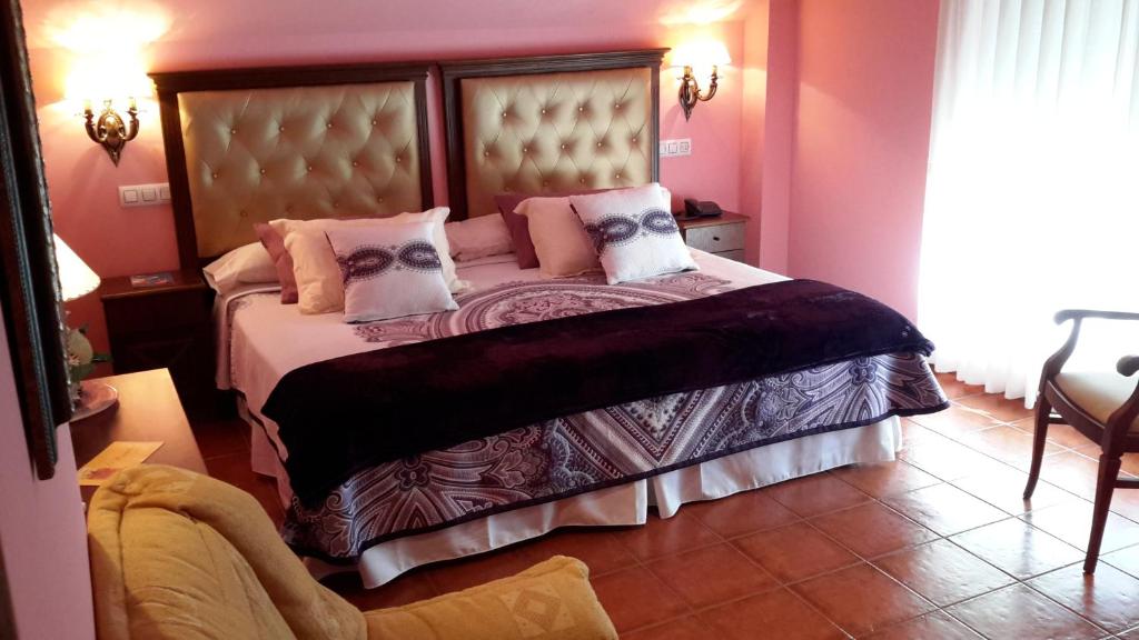 a bedroom with a large bed with pink walls at Hotel Boutique El Pescador in Cudillero