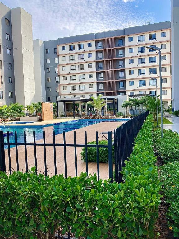 a building with a swimming pool in front of a building at Apto condomínio conforto e ótima localização in Lucas do Rio Verde